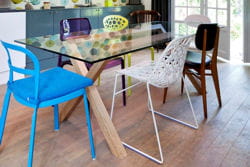 table en bois et verre entourée de chaises dépareillées