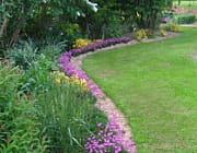 une pelouse bien entretenue contraste avec de belles plates-bandes. 